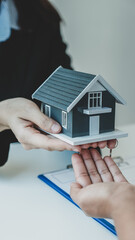 Hand a real estate agent hold the home model, and explain the business contract, rent, buy,...