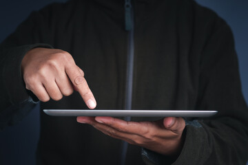 Close-up of a man hand holding a digital tablet and touching on the screen. Side view. New technology and multimedia concept
