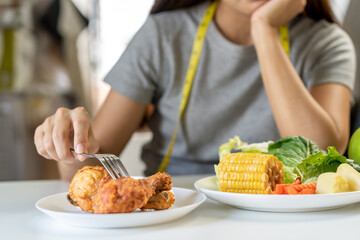 Diet, Dieting young asian women use fork at fried chicken, junk food not choose eat vegetables salad and fruits, eat green food is low fat good health, healthy Weight loss female person.