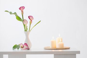 pink calla lily in vase  and burning candles on white background