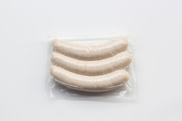 Top view of fresh bratwurst sausages packaged in vacuum plastic pack isolated on a white background.