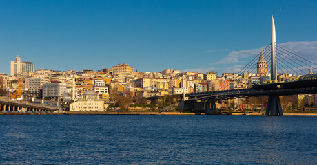 Fototapeta premium Scenic view of modern cityscape of Beyoglu district in Istanbul across Bosphorus and Golden Horn bay with views of cable-stayed metro bridge on sunny winter day, Turkey