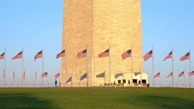 Flags of the United States near washington monument waving over blue sky