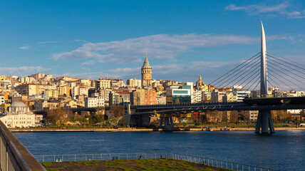 Fototapeta na wymiar Scenic view of modern cityscape of Beyoglu district in Istanbul across Bosphorus and Golden Horn bay with views of cable-stayed metro bridge on sunny winter day, Turkey
