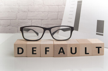 The word default is written on wooden cubes standing on the white surface of the table, THE GLASSES are on the cubes