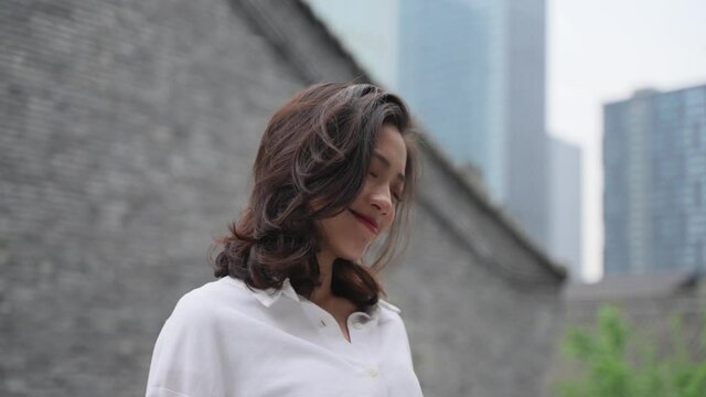 4k slow motion of lovely asian girl enjoy the day outdoor in the urban street with office building in the background beautiful Chinese young woman relax leaning on rails looking up smile