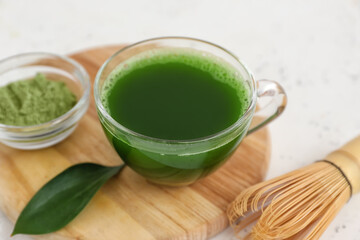 Cup of matcha tea, powder and chasen on white background