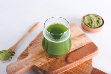Glass of matcha tea and powder on light background