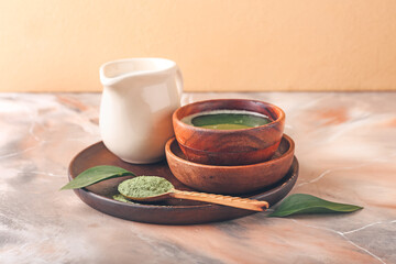 Bowl with matcha tea, milk and powder on table