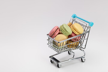 Multi-colored macarons in a cart for a supermarket. Close-up, copy space.