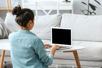 Beautiful young woman using laptop at home