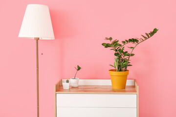 Modern chest of drawers and lamp near color wall in room