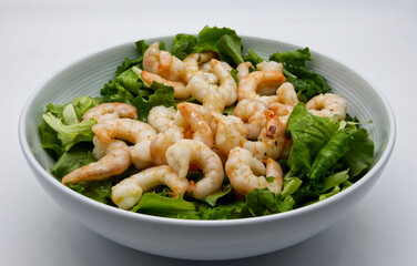 Fresh shrimp salad with lettuce on white dish.