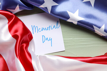 Fototapeta na wymiar Paper sheet with text MEMORIAL DAY and USA flag on color wooden background
