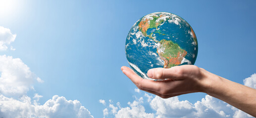 Hands holding a planet, earth on a background of nature blue sky with beautiful white clouds and sunlight.Sustain earth concept. Elements of this image furnished by NASA