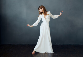Fototapeta premium Romantic woman in full growth on a gray background in a white dress Copy Space
