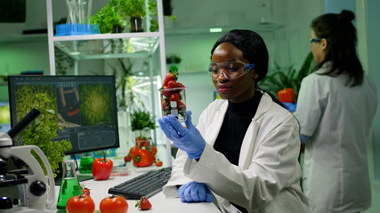 Biologist researcher looking at organic strawberry examining fruits for microbiology medical expertise. Chemists scientists working in pharmacology agriculture lab discovering genetic mutation on food