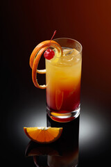 Cocktail tequila sunrise on a black reflective background.