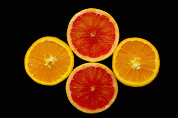 Composition with orange and grapefruit slices on a black background.