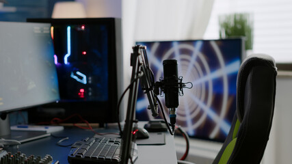 Game loading on display of RGB professional powerful computer and stream chat is prepared for virtual tournament. Streaming professsional microphone in empty gaming home studio with neon lights.