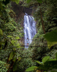 Woman walking in a bridge in front of a beautiful waterfall