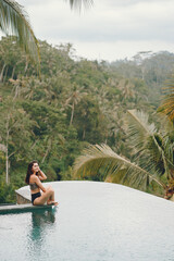 Fototapeta premium Woman in a swimming pool on a jungle view