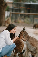 Woman in the reserve is playing with a kangaroo