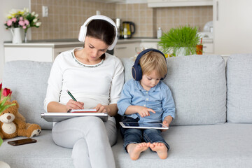 Mother, working on her laptop and taking phone calls, child playing next to her at home