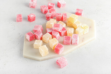 Board with Turkish delight on light background