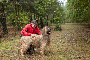A senior man snuggling and hugging with his dog, close friendship and loving bond between owner and bearded collie dog.