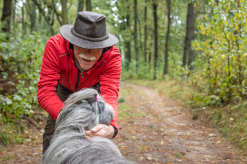 A senior man snuggling and hugging with his dog, close friendship and loving bond between owner and bearded collie dog.