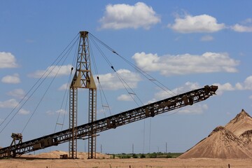Kansas Sand Pit with a sand conveyer, blue sky, and white clouds in Hutchinson Kansas USA. That's bright and colorful.