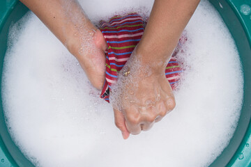 Female hands wash clothing by hand with detergent in basin. selective focus and space for text.