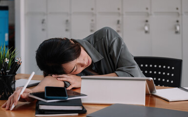 Fototapeta na wymiar Overworked tired businesswoman sleeping on table in office. Young exhausted girl working from home. Woman using laptop. Entrepreneur, business, freelance work, student, stress, work from home concept.