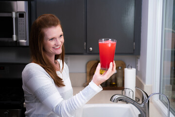 Red Head Caucasian Woman Mother Mom in Kitchen Looking at Blended Red Health Drink Ingredients Smiling Happy and Thoughtful