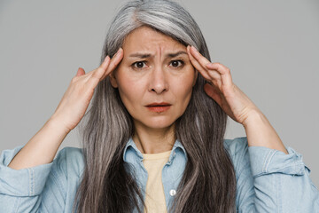 Unhappy white-haired woman with headache rubbing her temples