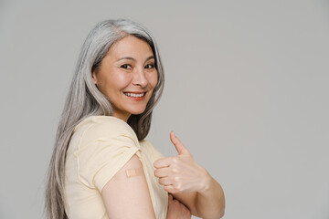 Smiling white-haired woman with bandage gesturing thumb up