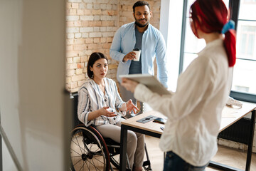 Fototapeta premium Multiracial young three colleagues talking and working in office