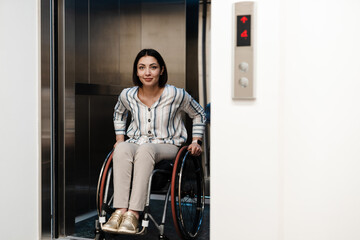 White young woman smiling while sitting in wheelchair at elevator
