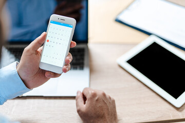 Man using mobile phone while working with laptop in office