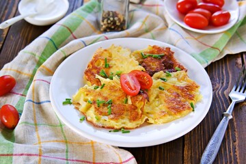 Potato fritters on a white plate on a wooden background. Jewish food.