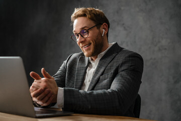 The happy man talking by video call on a laptop while shaking hands in the studio