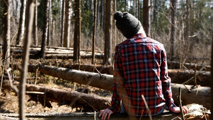 fragile girl lumberjack. A girl in the forest sits on a fallen tree