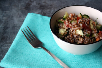 Salad of buckwheat, tomatoes, cucumbers and dill with olive oil in a white bowl. Vegetarianism. Lean food.