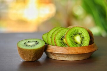 Sliced and half of kiwifruit (Actinidia chinensis) on wooden table with bokeh background.Sweet,sour and freshness taste.Have a lot of fiber, vitamins and minerals.Food,Fruits or healthcare concept.