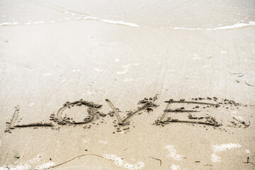 Hand written sing love on a sand. Romantic message on a beach surface. Visual expression of passion through artistic skill