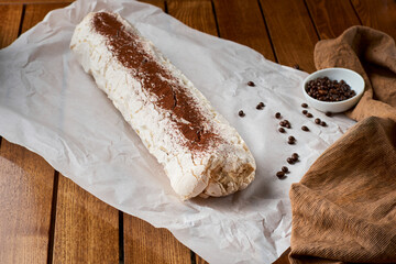 Close-up shot of meringue roll with coffee filling sprinkled with powdered sugar