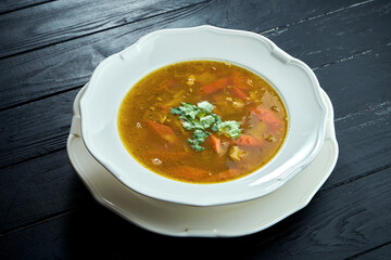 Close up view Chorba soup or stew with beef, herbs and hot pepper in white bowl on wooden background, Traditional turkish cuisine