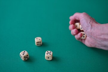 Cropped photo of hand throwing dices on the green table