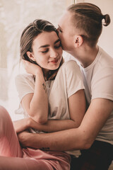 Couple at home dressed in home clothes sitting on the windowsill